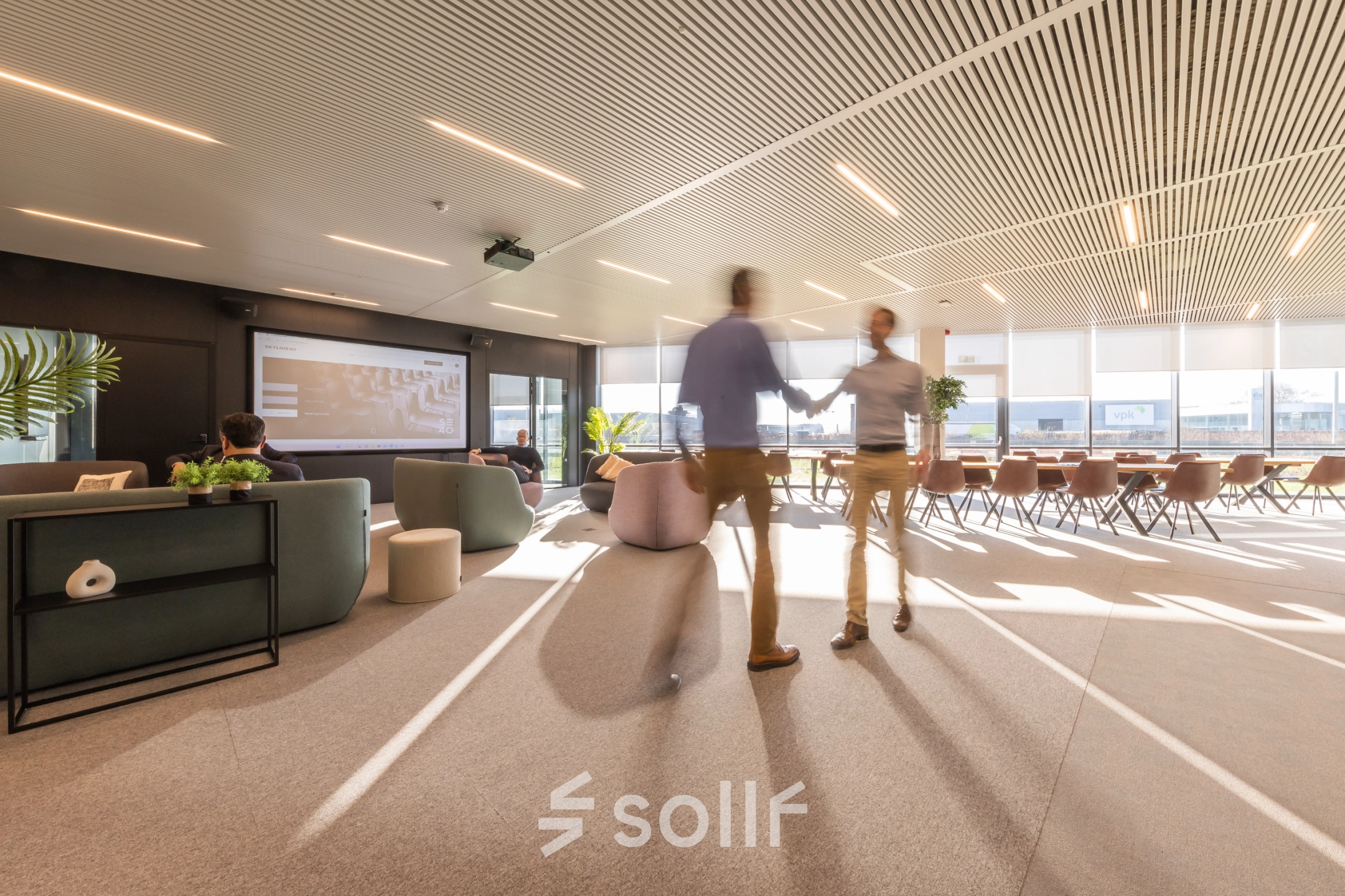 Moderne kantoorruimte te huur in Aalst met comfortabele zitplaatsen en zakelijke professionals die overleggen. Licht interieur en ruime opstelling aan de Korte Keppestraat 19 voor een inspirerende werkomgeving.