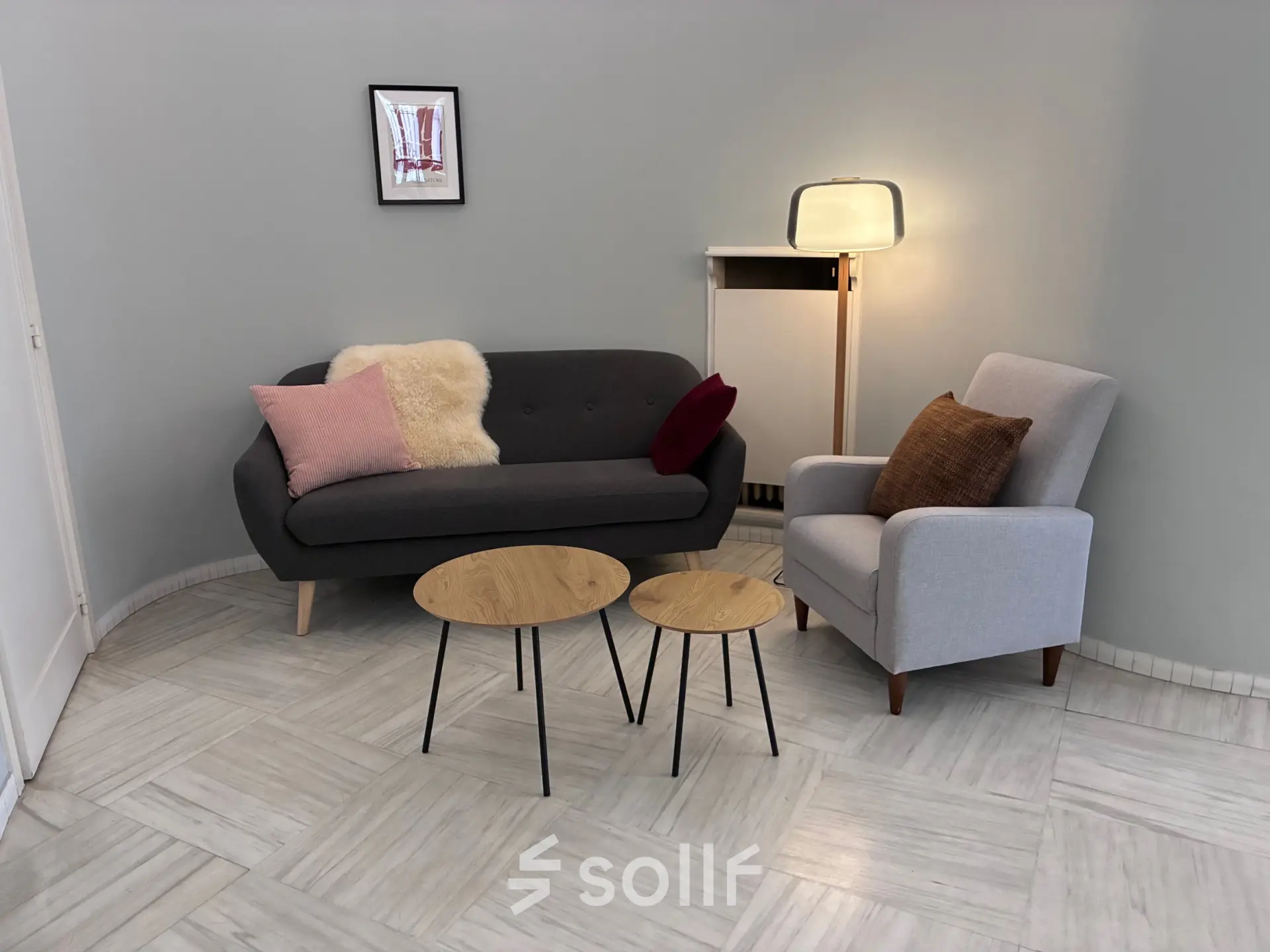 Gezellige loungehoek in kantoor te huur op Avenue Palmerston 3, Brussel Europese Wijk. Grijze zitbank met kussens, bijzettafels en een staande lamp, ideaal voor ontspanningsmomenten.