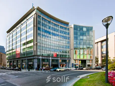 Zakelijk kantoorgebouw op het Robert Schumanplein 2-4 in Brussel Europese Wijk, met moderne glazen gevels en omringd door wegen en auto's, beschikbaar voor kantoor te huur.