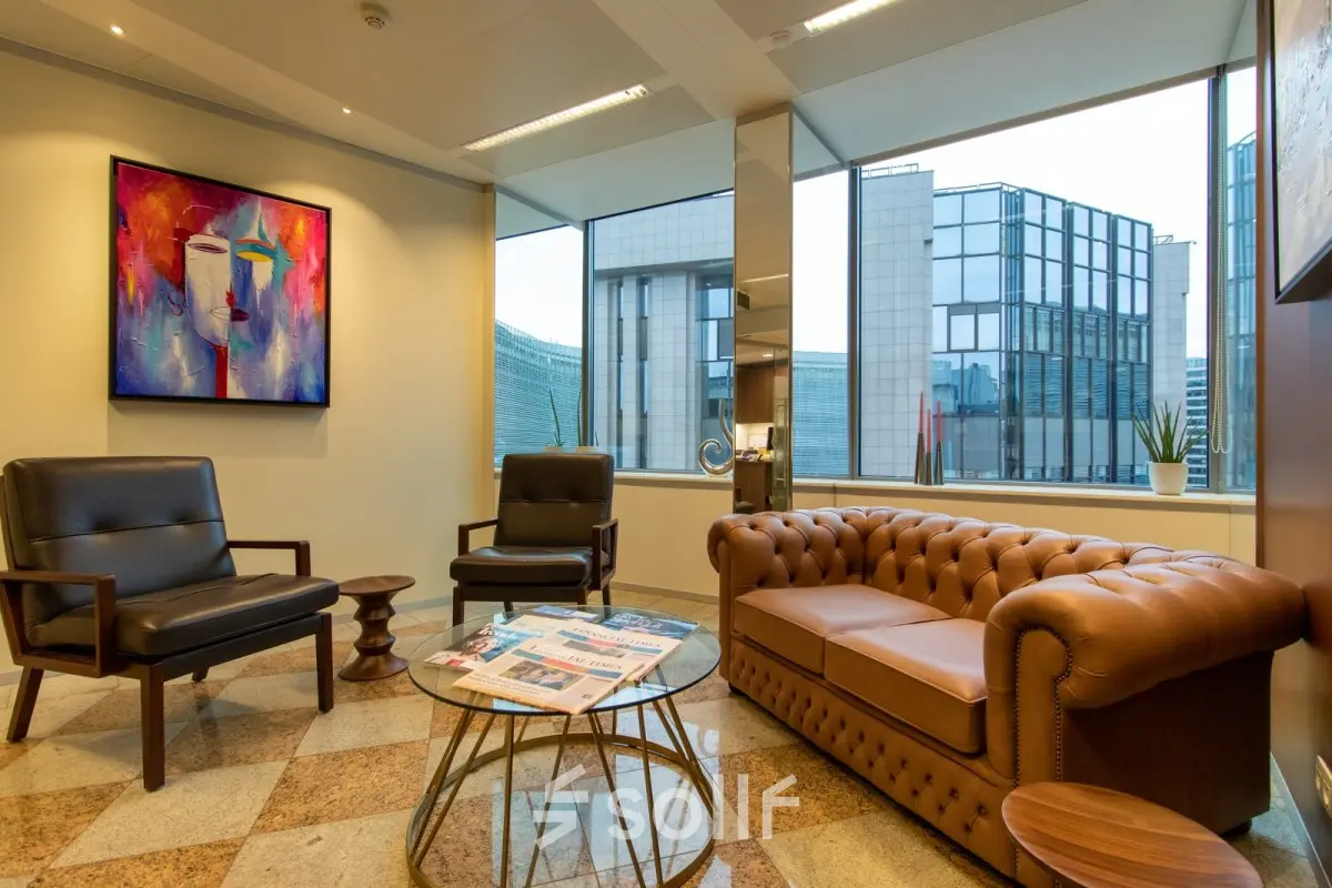 Kantoorruimte te huur op Robert Schumanplein 2-4 in Brussel Europese Wijk, met moderne meubels, kunst aan de muur en uitzicht op omliggende gebouwen.