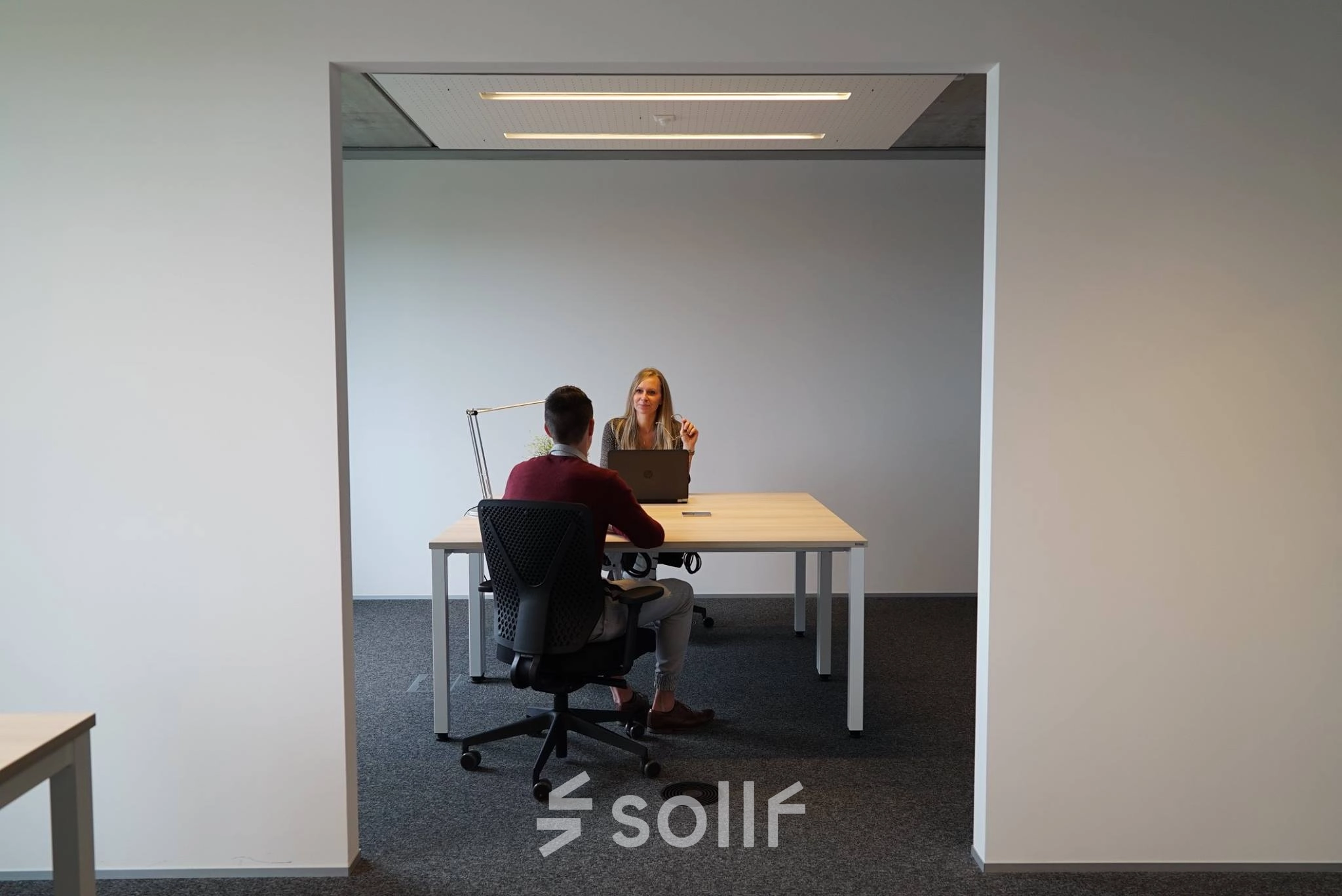 Zakelijke bespreking in een moderne kantoorruimte te huur op Diamantstraat 8, Herentals, met twee personen aan een tafel.