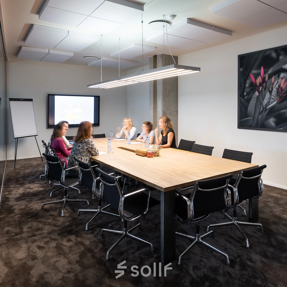 Vergaderruimte in kantoor te huur op Philipssite 5, Leuven, met vijf personen aan een grote tafel, scherm en flip-over in de achtergrond.