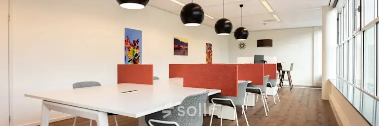 Helles Büro mit modernen Möbeln und einem großen Tisch, ideal zum Büro mieten. Kunstwerke an den Wänden ergänzen die Atmosphäre.