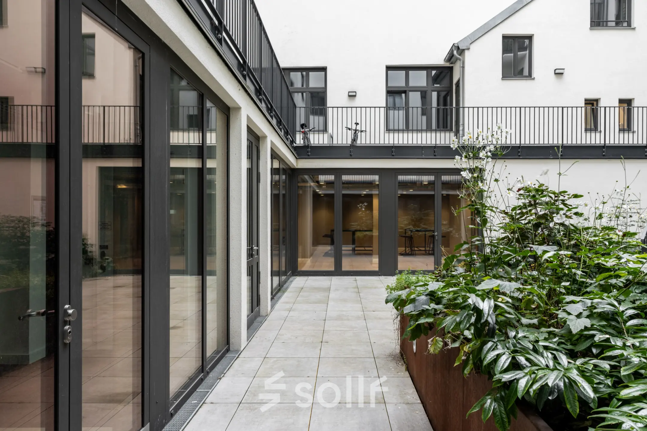 Innenhof in der Chausseestraße 29, umgeben von Büroflächen in Berlin Kreuzberg, mit modernen Glastüren und gepflegtem Grünbereich.
