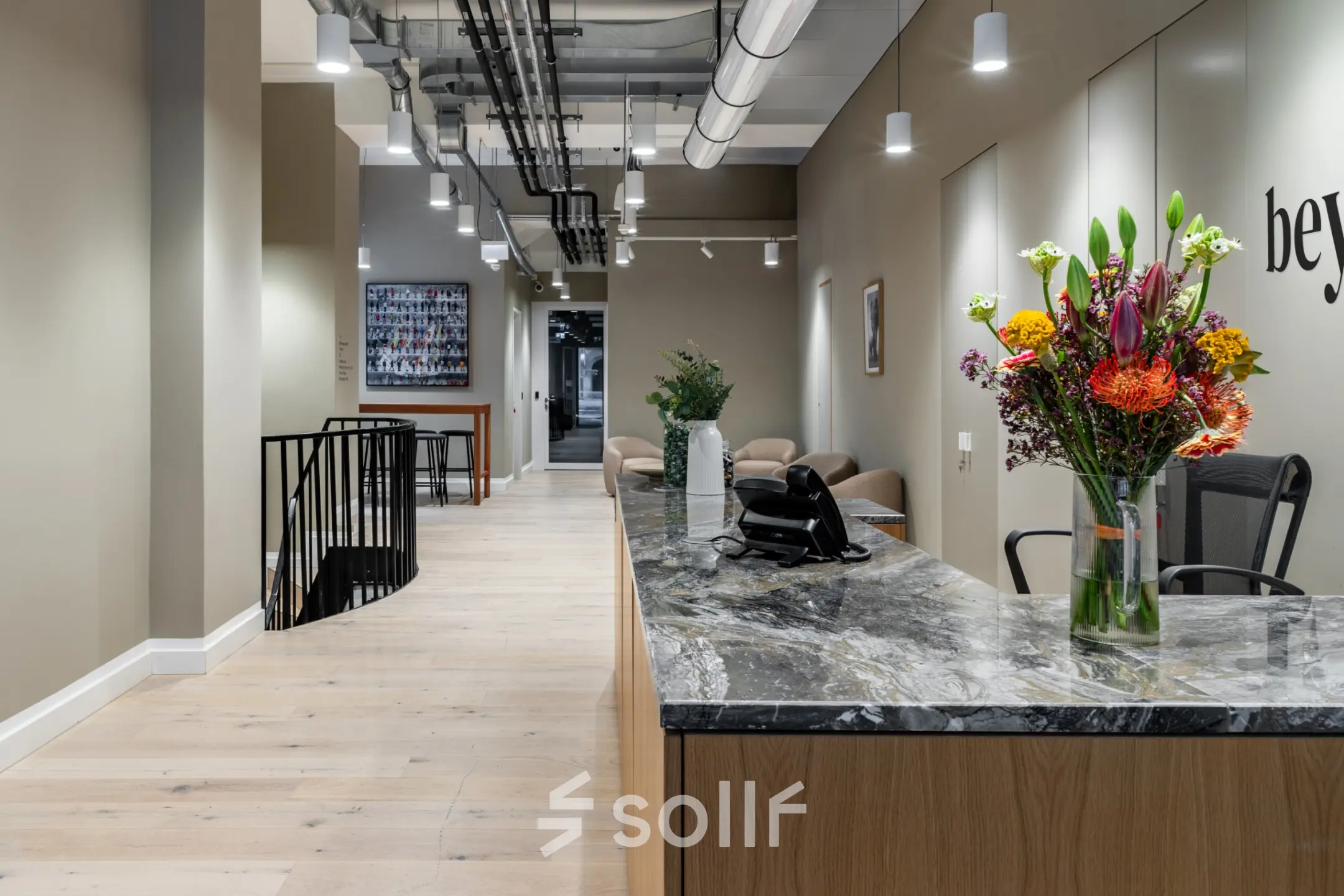 Modernes Büro in der Chausseestraße 29, Berlin Kreuzberg, mit stilvollem Empfangsbereich und Marmor-Theke. Perfekt für büroraum mieten. Große Blumenarrangements zieren den Raum.