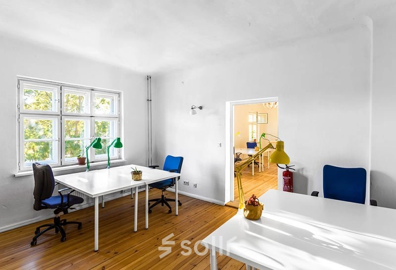 Helles Büro im Berlin Lichtenberg mit großen Fenstern und drei weißen Tischen, ideal zum Büro mieten. Moderne Bürostühle und dezente Dekorationen runden die Einrichtung ab.