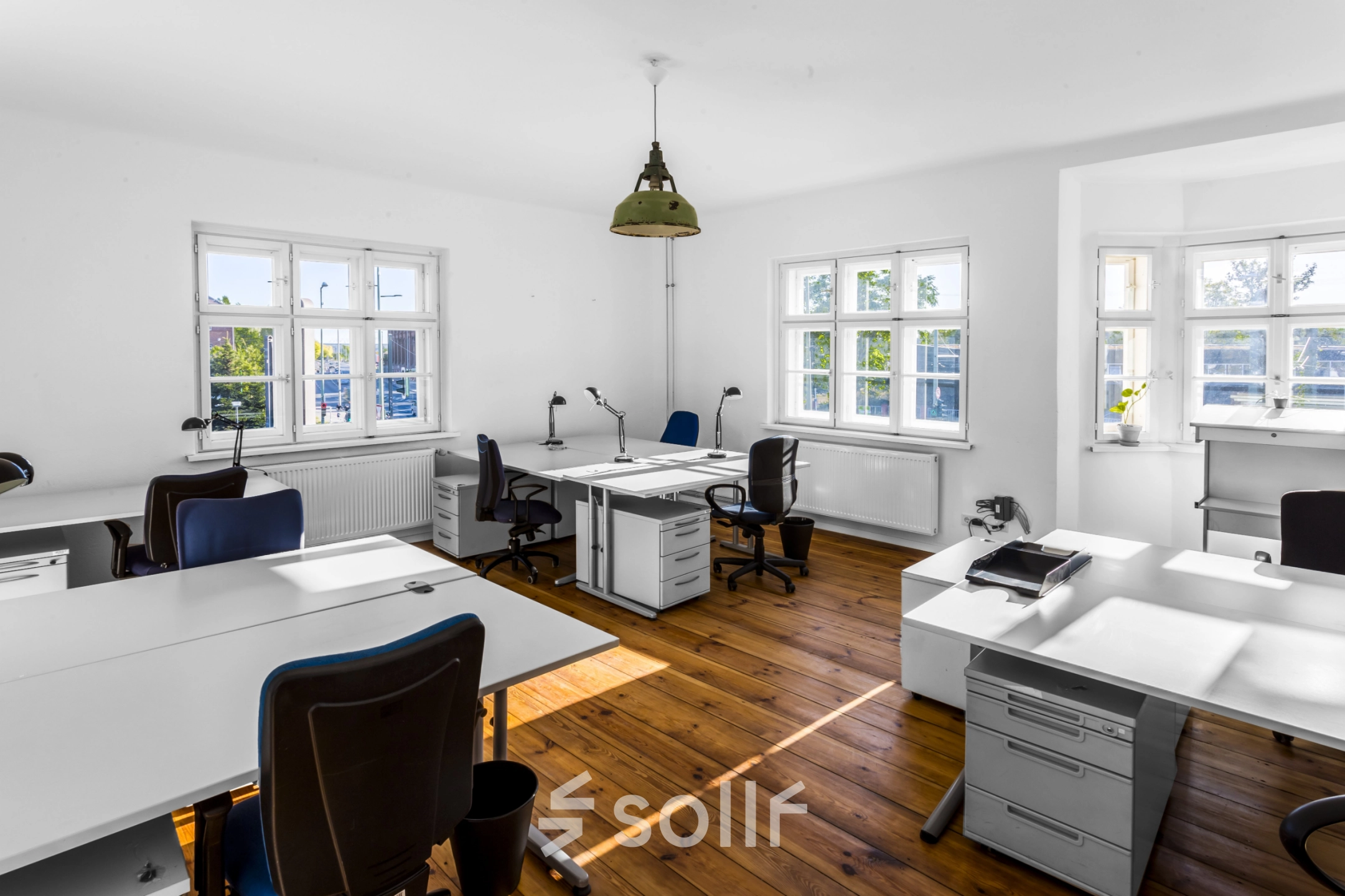 Helles Büro mit Holzboden, mehreren weißen Schreibtischen und Stühlen im Berlin Lichtenberg. Perfekt zum Büro mieten oder Büroraum mieten.