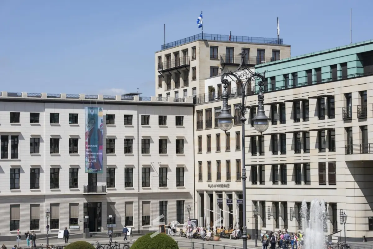 Außenansicht des Bürogebäudes am Pariser Platz 6a, Berlin Mitte, mit mehreren Personen, die das Gebäude betreten oder verlassen.