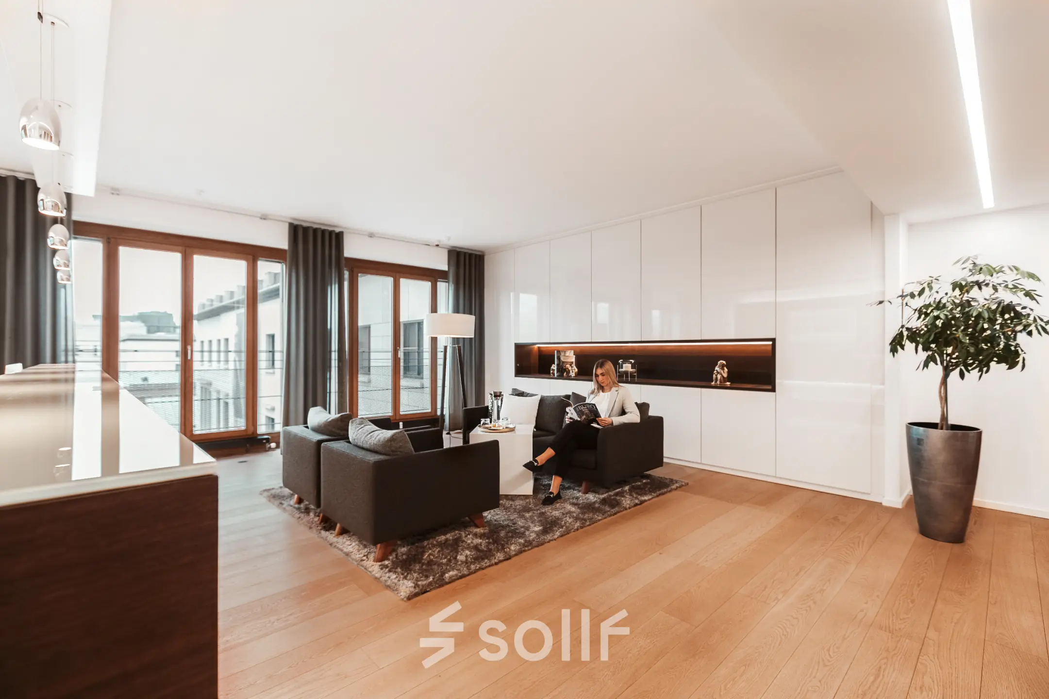 Moderner und heller Büroraum mit großen Fenstern, stilvollen Möbeln und einer Person bei der Arbeit. Ideal zum Büro mieten in Berlin Mitte, Pariser Platz 6a.