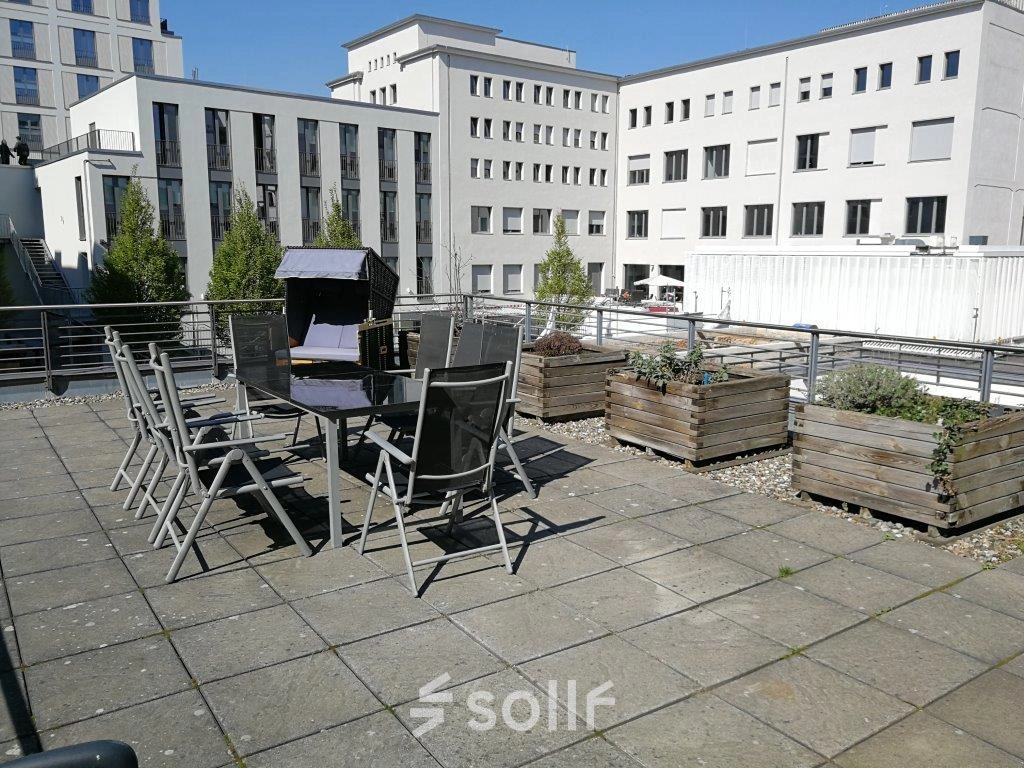 Rooftop-Terrasse mit Tischen und Stühlen in Berlin Mitte, ideal, um nach dem Büro mieten eine Pause an der frischen Luft zu genießen.