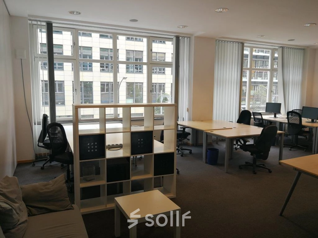 Helles Büro in Berlin Mitte mit großen Fenstern, mehreren Arbeitsplätzen und einer Couch; ideal zum Büro mieten.