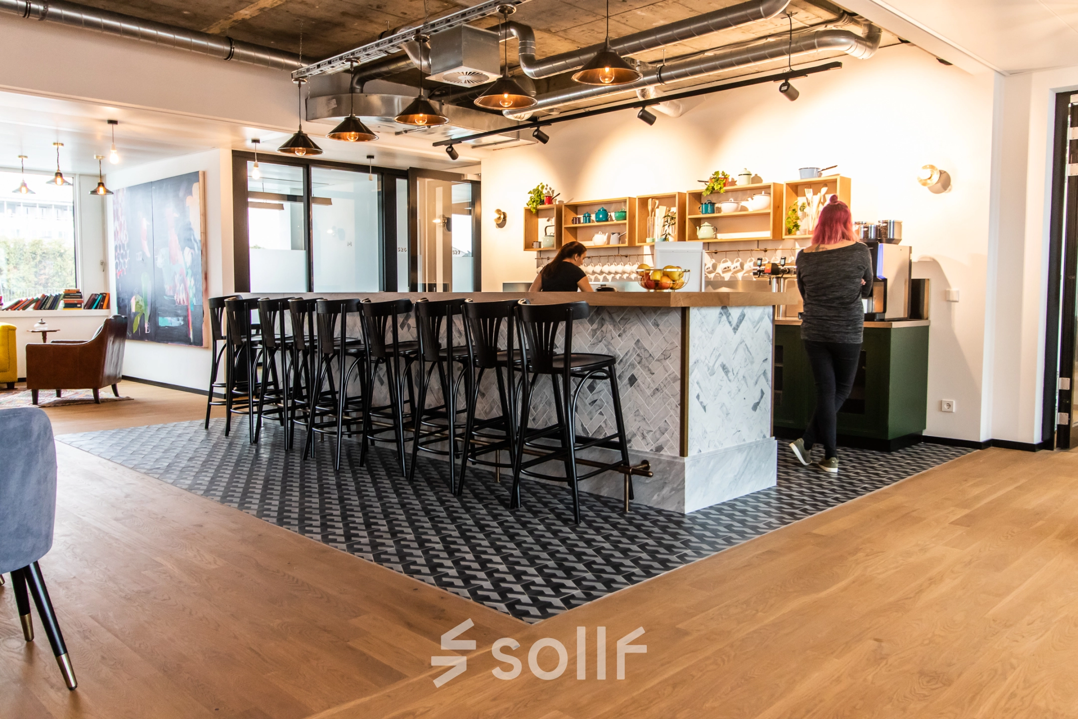 Moderner Büroraum in München Altstadt mit stilvoller Einrichtung und Personen, die an einem Bartresen arbeiten. Perfekte Option, um Bürofläche zu mieten in der Herzogspitalstraße 24.