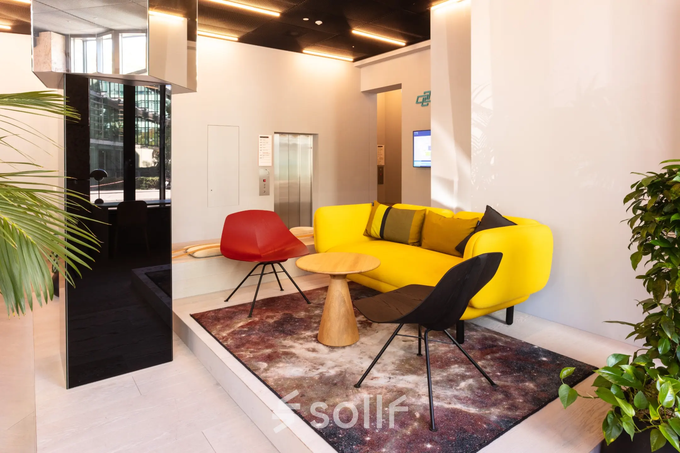 Moderne Empfangslobby mit buntem Sofa und stilvollen Sesseln, ideal für diejenigen, die Bürofläche mieten möchten. Elegante Einrichtung und helle Atmosphäre bieten einen einladenden Raum.