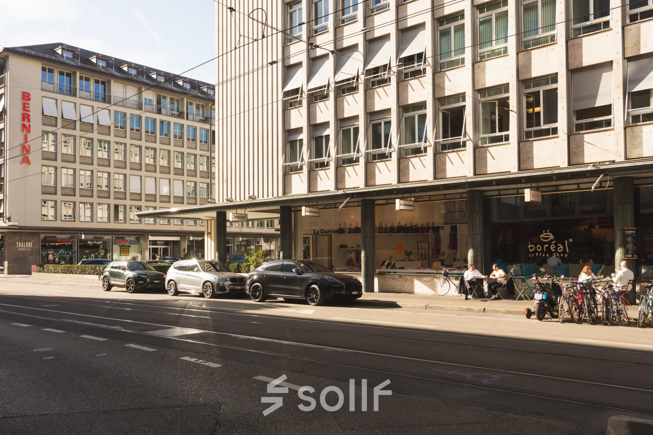 Straßenansicht vor Talacker 41 in Zürich City mit geparkten Autos und Menschen, die sich draußen entspannen. Keine Büros im Bild.