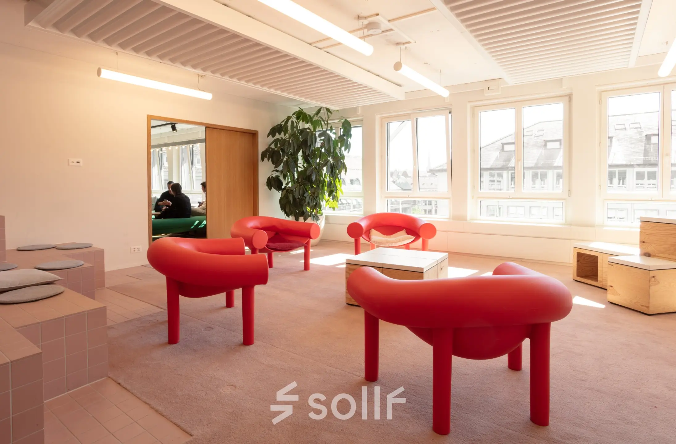 Helles Büro in Zürich City mit roten Sitzgelegenheiten und großen Fenstern, ideal zur Miete als Büroraum mit möbliertem Interieur.