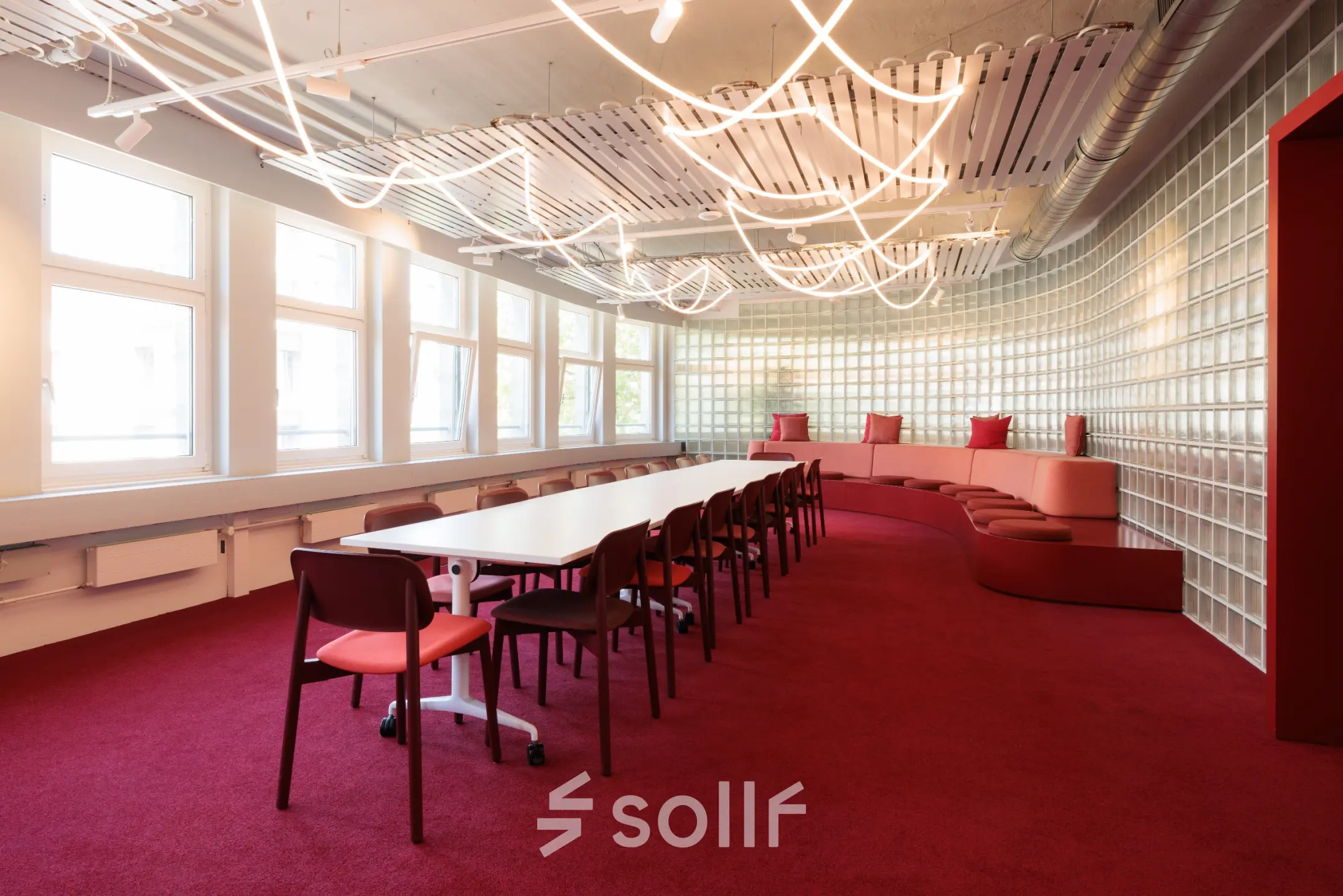 Modernes Büro zur Miete in der Uraniastrasse 31, Zürich City, mit stilvollem Tisch, roten Stühlen und geschwungener Sitzbank auf rotem Teppich.
