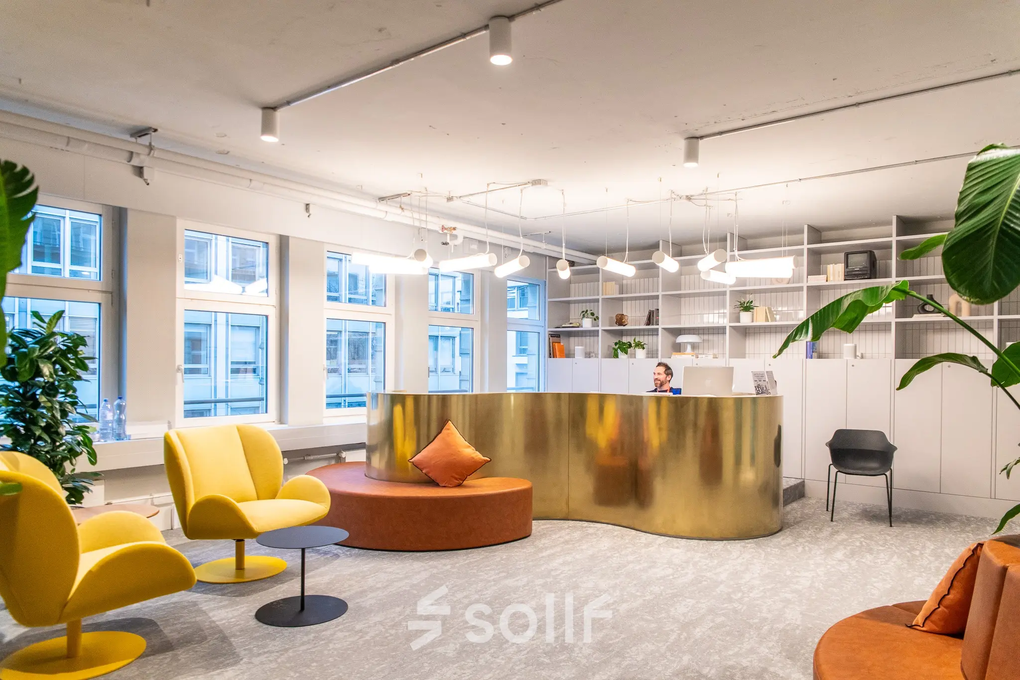 Modernes Büro in der Uraniastrasse 31, Zürich City, mit stilvollen Möbeln, auffälliger goldener Rezeption und Pflanzen. Eine Person empfängt Besucher.