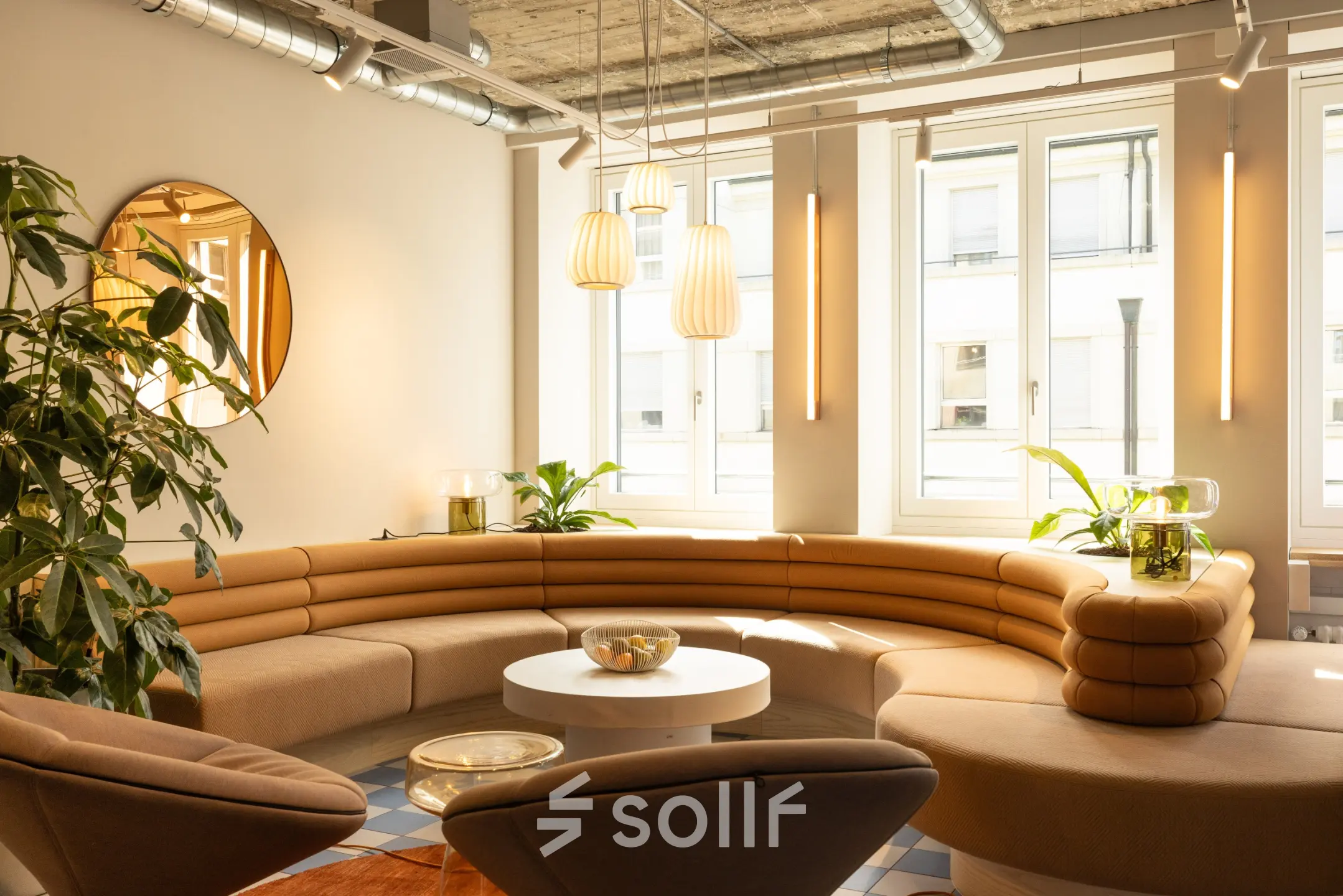 Heller, moderner Büroraum mit eleganter, geschwungener Ledercouch, runden Tischen und großen Fenstern in Zürich Enge. Ideal für Bürofläche mieten.