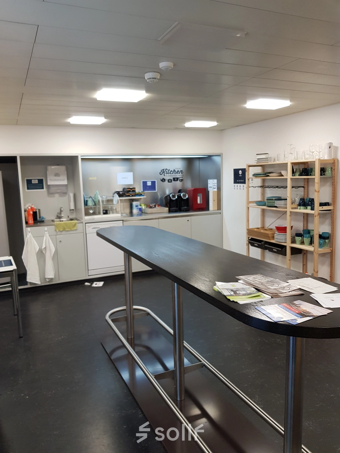 Möblierte Pantry mit hohen Tischen und Regalen in Mythenquai 26, Zürich Enge. Perfekt, um als Bürofläche zu mieten und für Pausen oder Meetings zu nutzen.