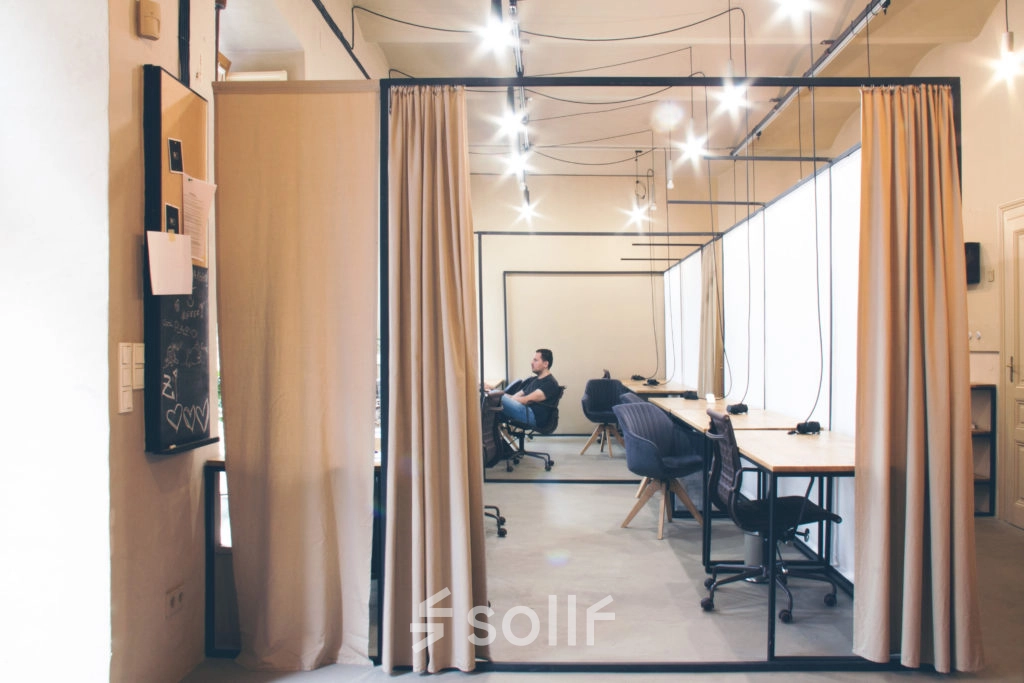 Modern office space with workstations and a person engaged in business activities at Zimmermanngasse 8, 1090 Vienna. Ideal office to rent with sleek design.