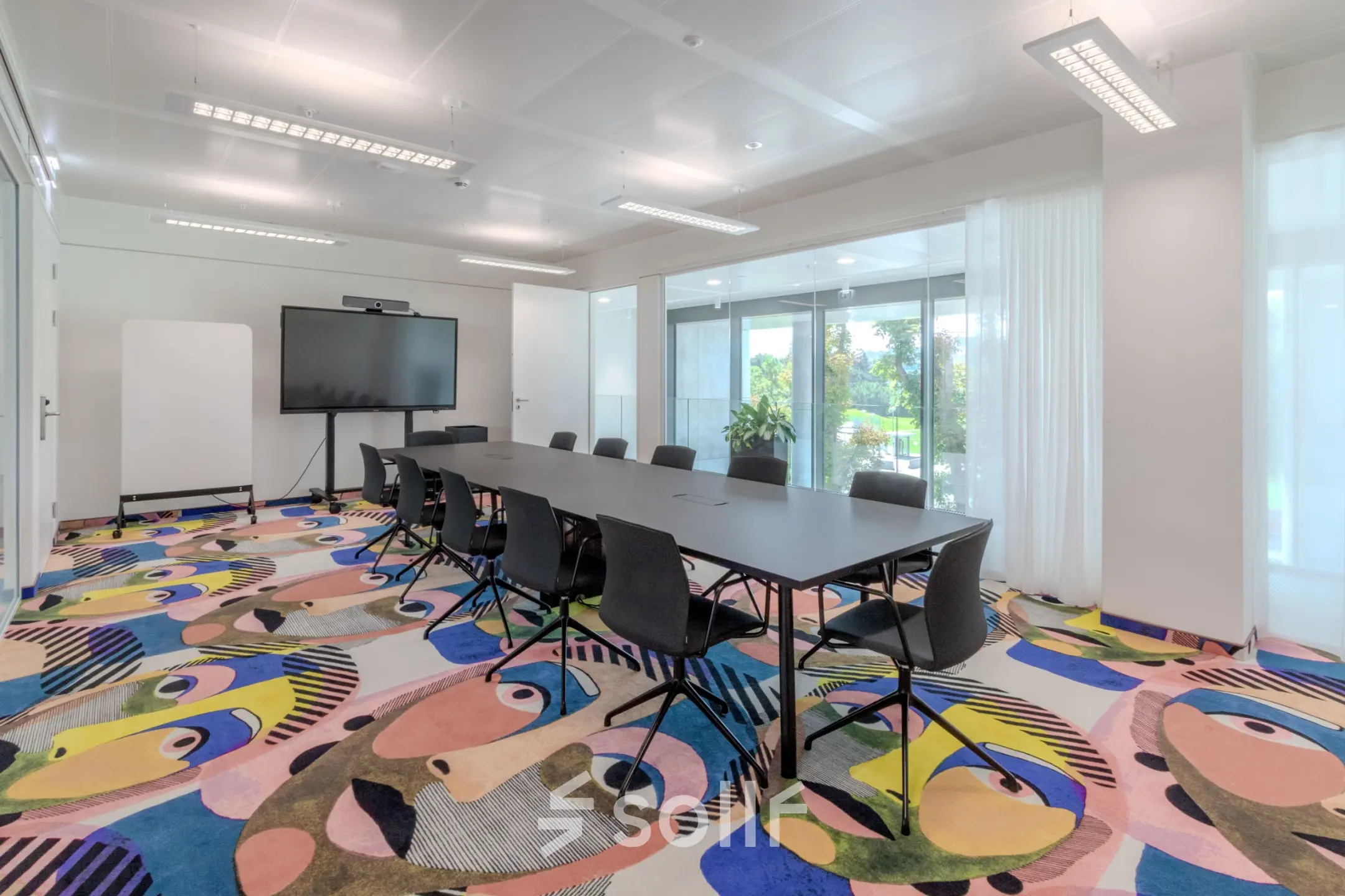 Bright office space in Siemensstraße 89, 1210 Vienna with colorful carpet, long conference table, and large screen; ideal for office space rental.