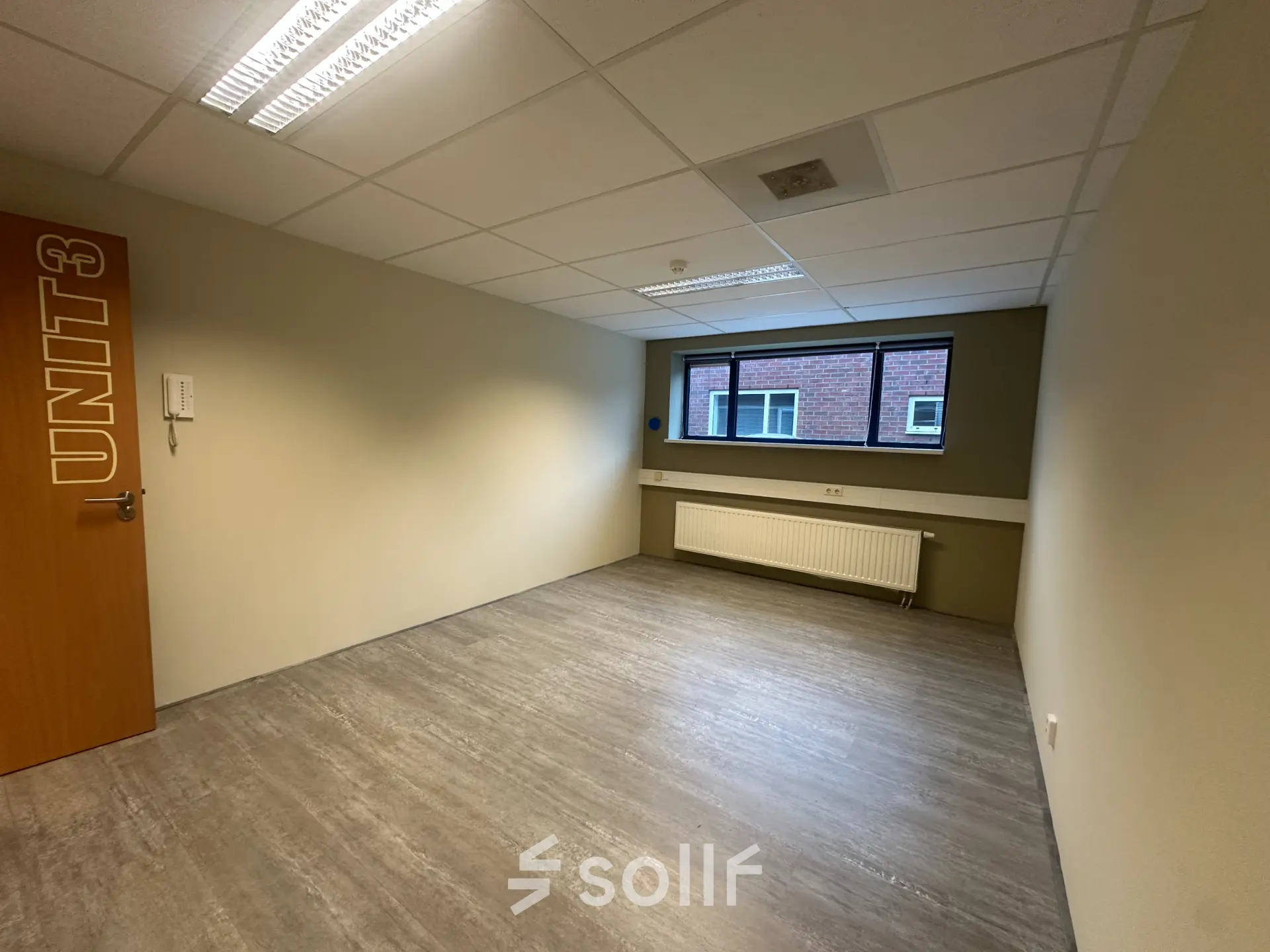 Empty office space at Hollandse Kade 38, Abcoude, featuring a neutral-toned interior with large window and overhead lighting, available for rent. Ideal for setting up your next office to rent.