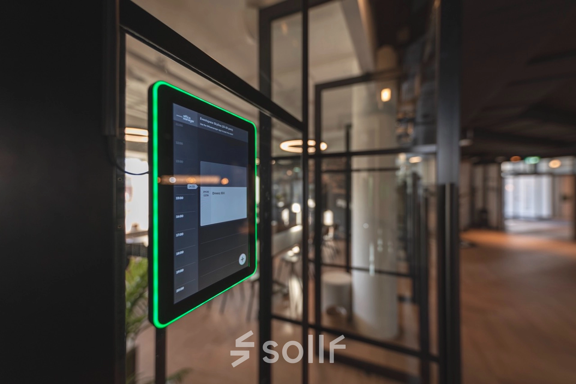 Modern office space for rent at Egbert Gorterstraat 2-14 in Almelo, featuring glass partitions and a digital schedule display panel, offering a tech-friendly environment.