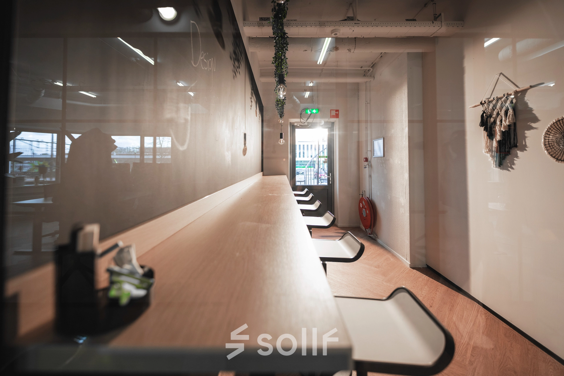 A sleek and modern open-floor workspace featuring a long wooden countertop with high stools, perfect for office space rental in Almelo's Egbert Gorterstraat 2-14.