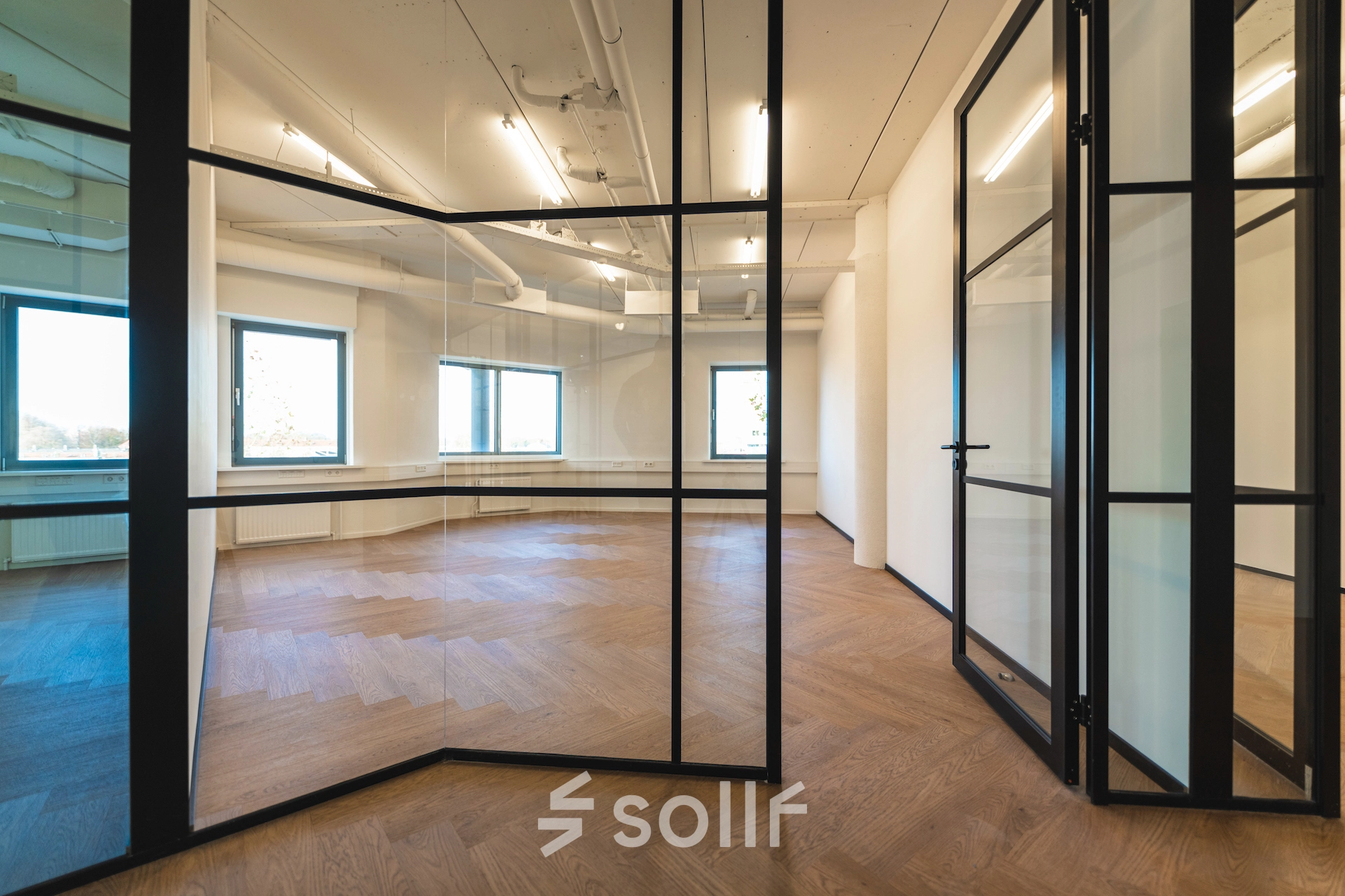 Modern, spacious office space rental at Egbert Gorterstraat 2-14 in Almelo, featuring large windows and stylish wooden flooring, offering natural light and a sleek design.