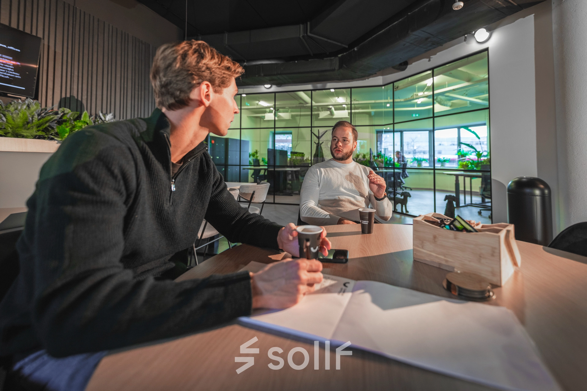 Two professionals engaged in a business discussion at a modern, furnished office space at Egbert Gorterstraat 2-14, Almelo. The bright interior creates an ideal environment for office space rental.
