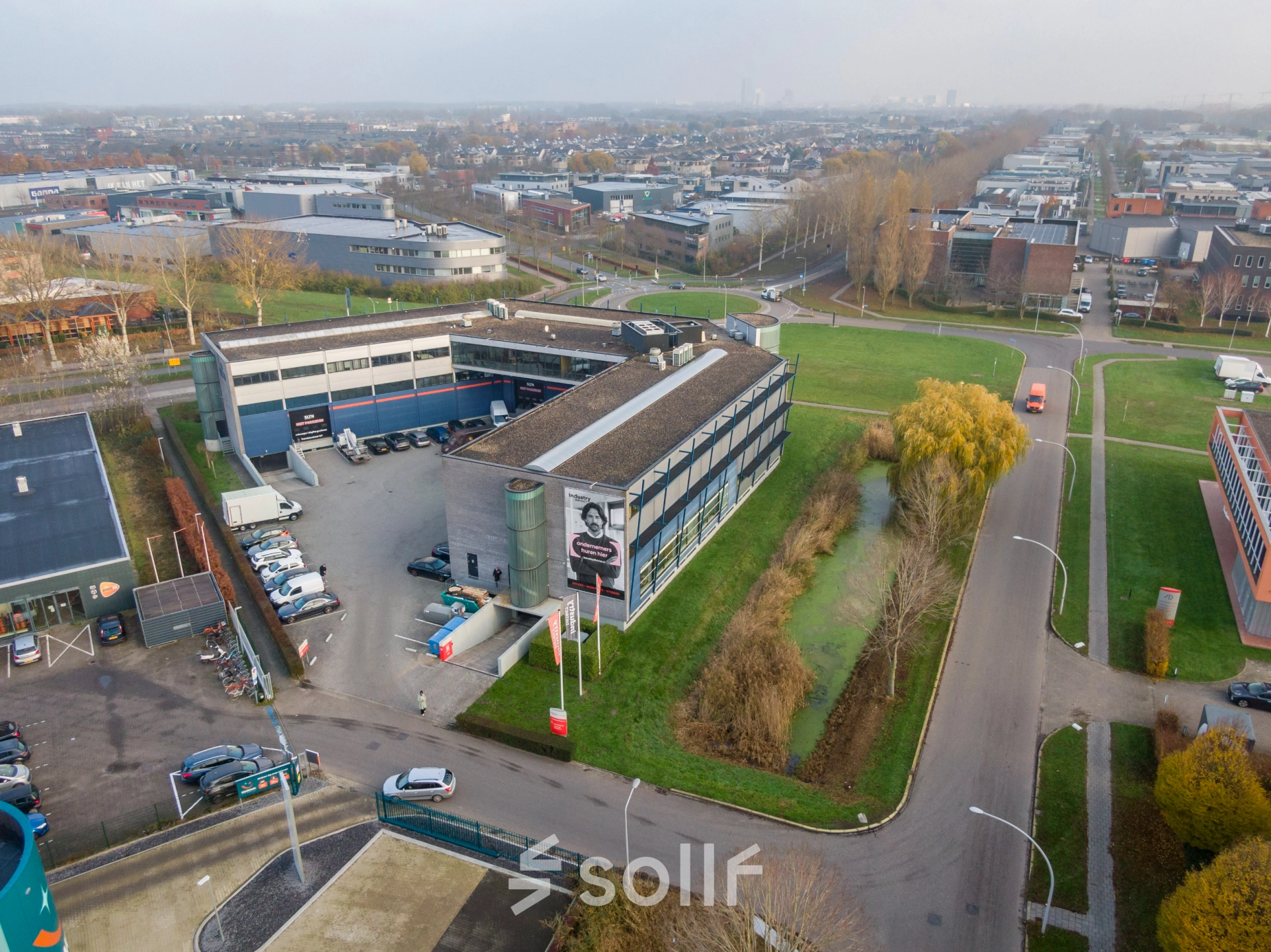 Aerial view of the office building located at Transistorstraat 151 in Almere Poort, Almere, showing the exterior surroundings and parking area. Ideal for office space rental in a convenient business location.