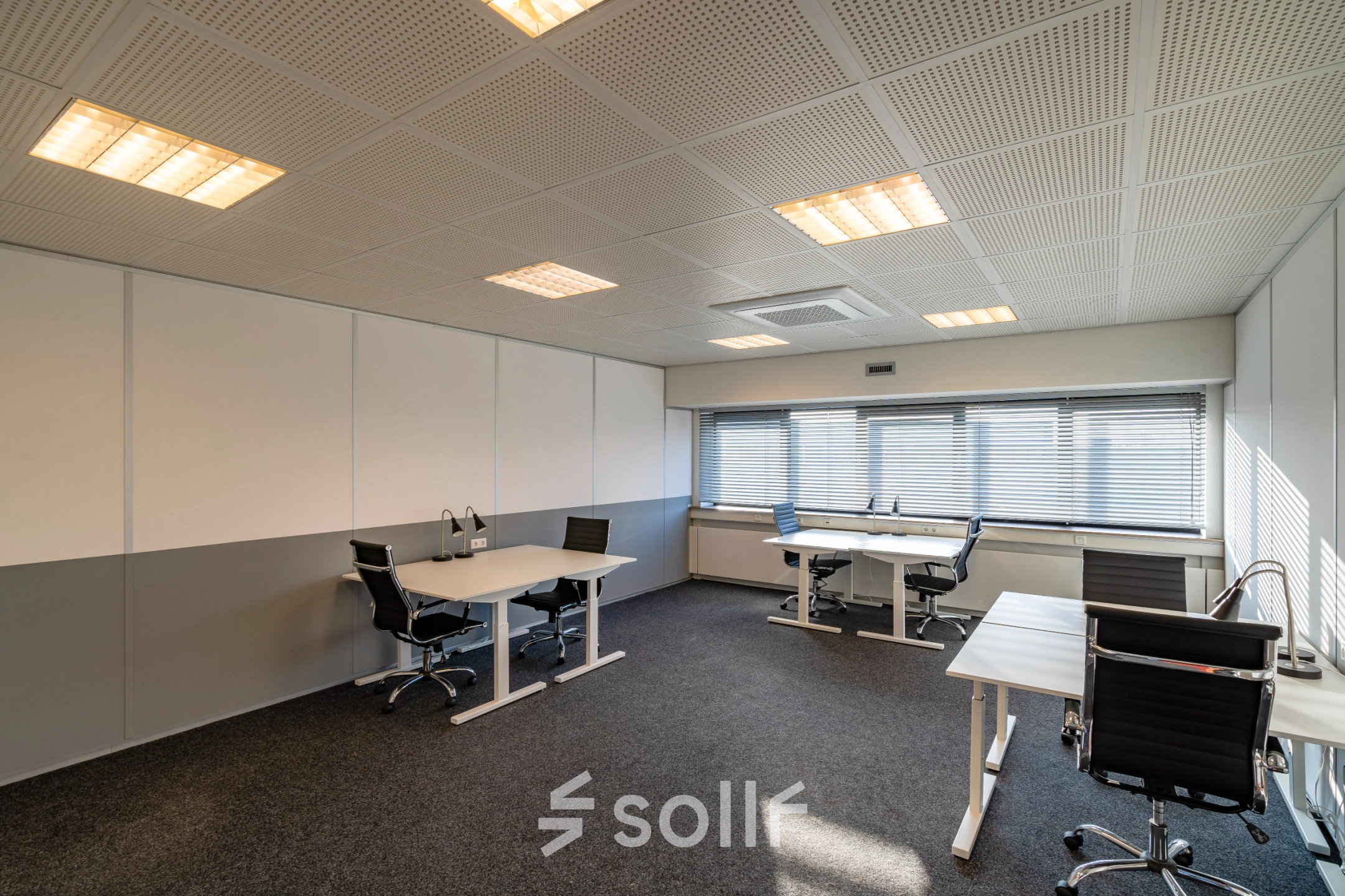 Modern workspace at Transistorstraat 151, featuring several desks and chairs, ideal for office space rental in Almere Poort. The room is well-lit with large windows and simple decor.