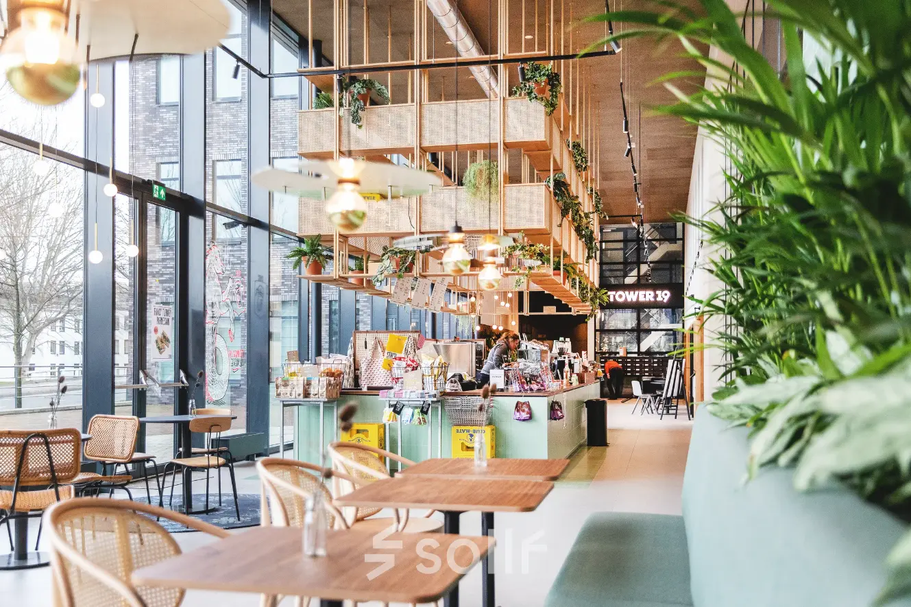 A vibrant workspace in Almere Stad featuring modern furniture, lush greenery, and ample natural light, perfect for office space rental.