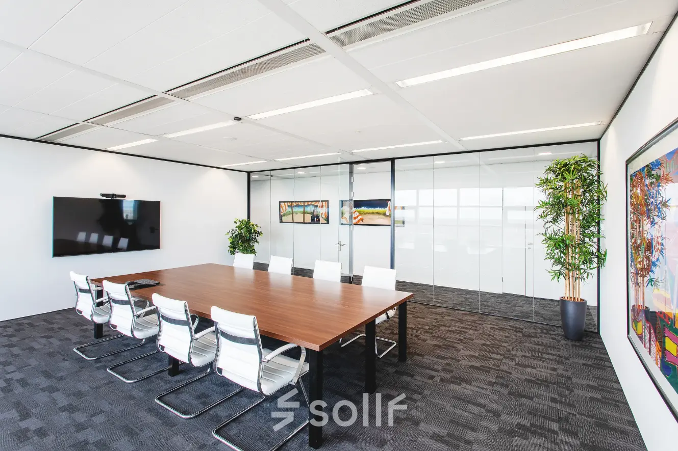 Spacious conference room with a large wooden table, modern chairs, and a digital screen, ideal for office space rental in Almere Stad.