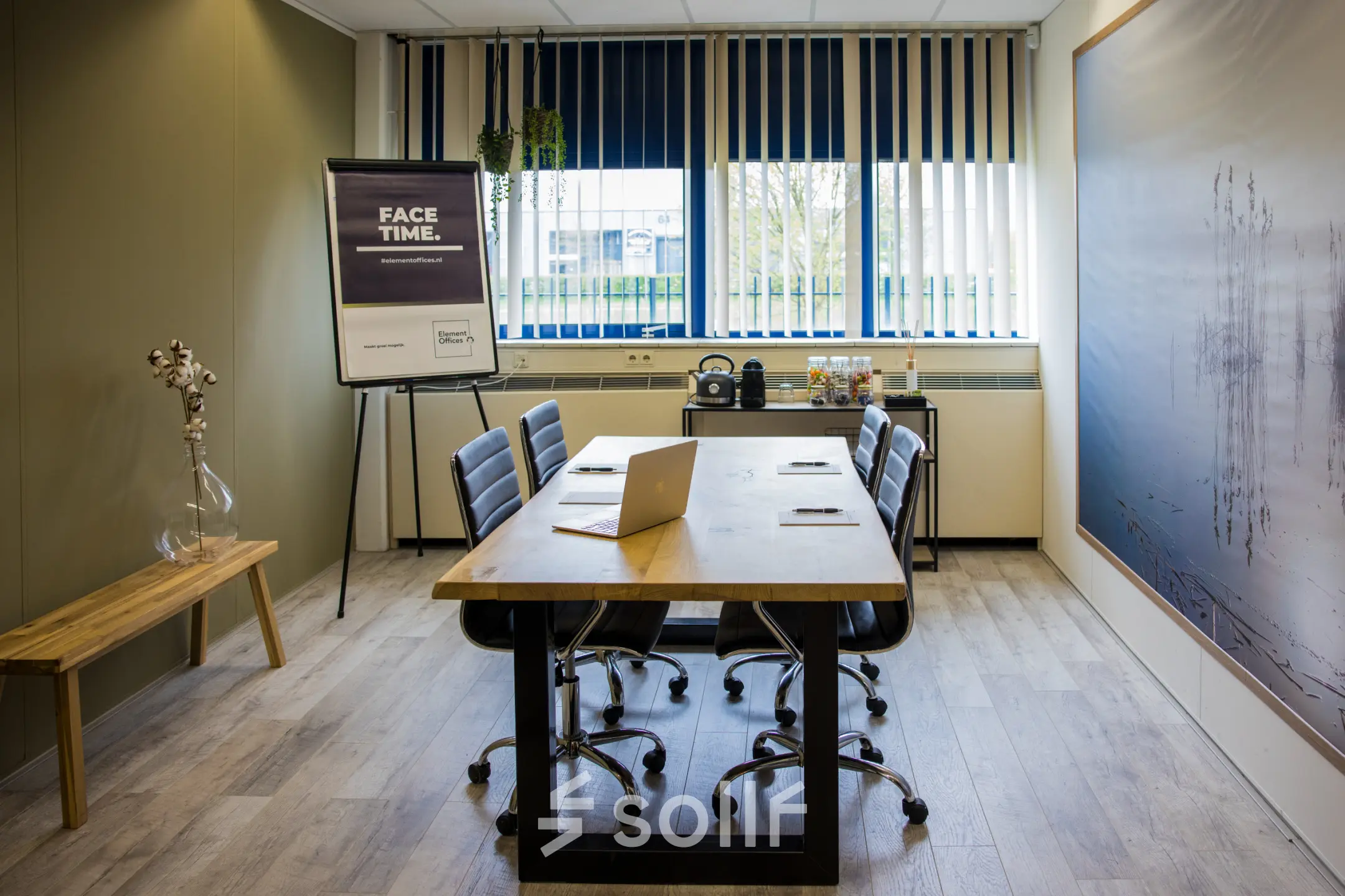Modern meeting room with wooden table, leather chairs, flip chart, and a laptop. Ideal office space rental in Almere Stad for collaborative work.