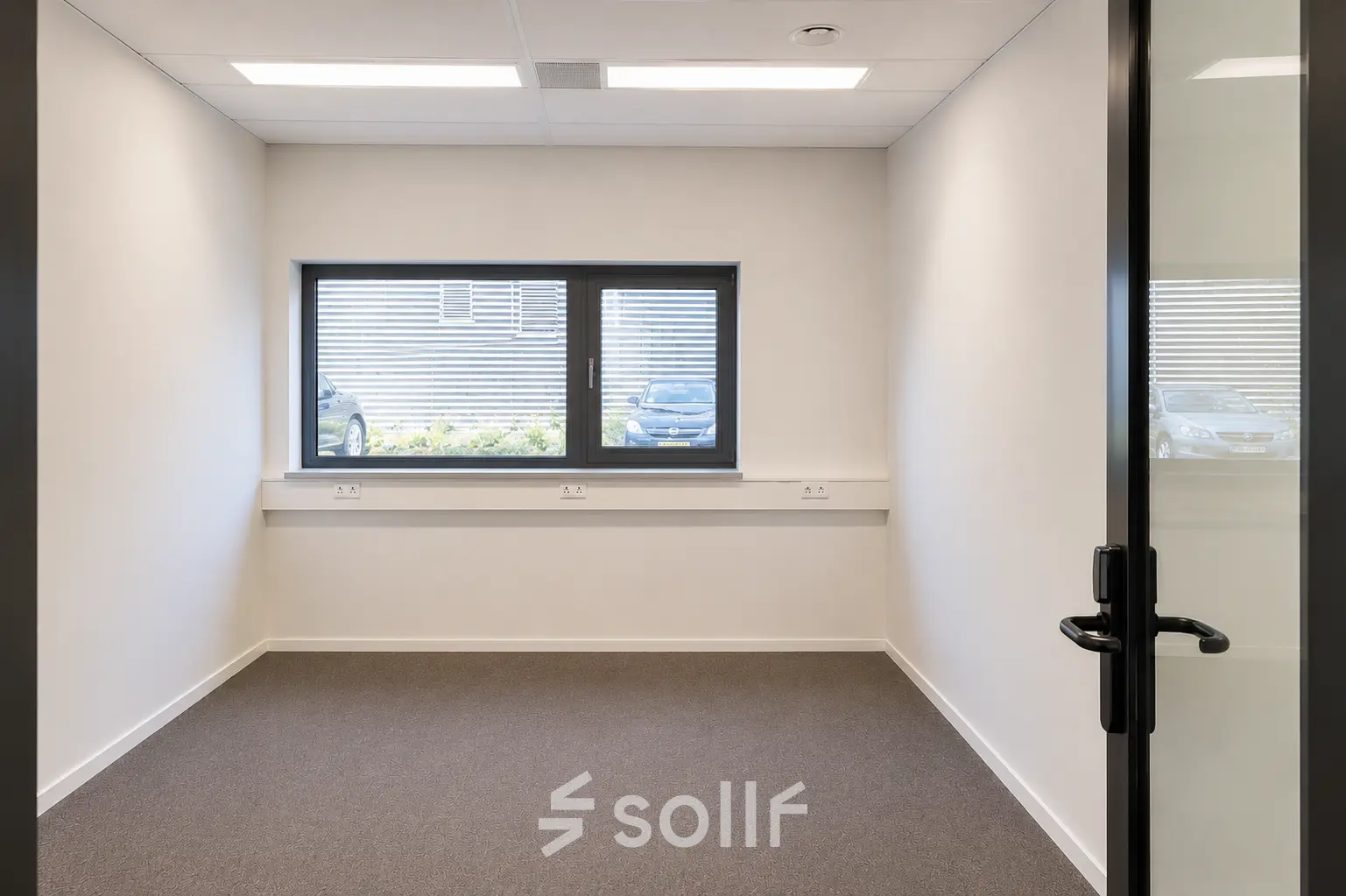 A bright, unfurnished office space available for rent at Veluwezoom 15, Almere Stad, featuring a large window with outdoor views.
