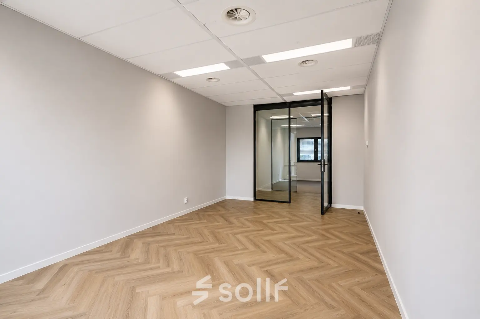 Empty office space at Veluwezoom 15, Almere Stad featuring a glass door and herringbone floor, ideal for office space rental.