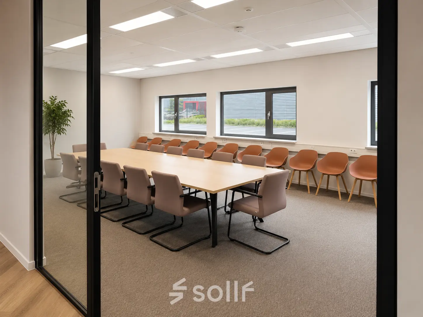 Conference room with a long table surrounded by chairs, featuring natural light through large windows at Veluwezoom 15, ideal for office space rental in Almere Stad.