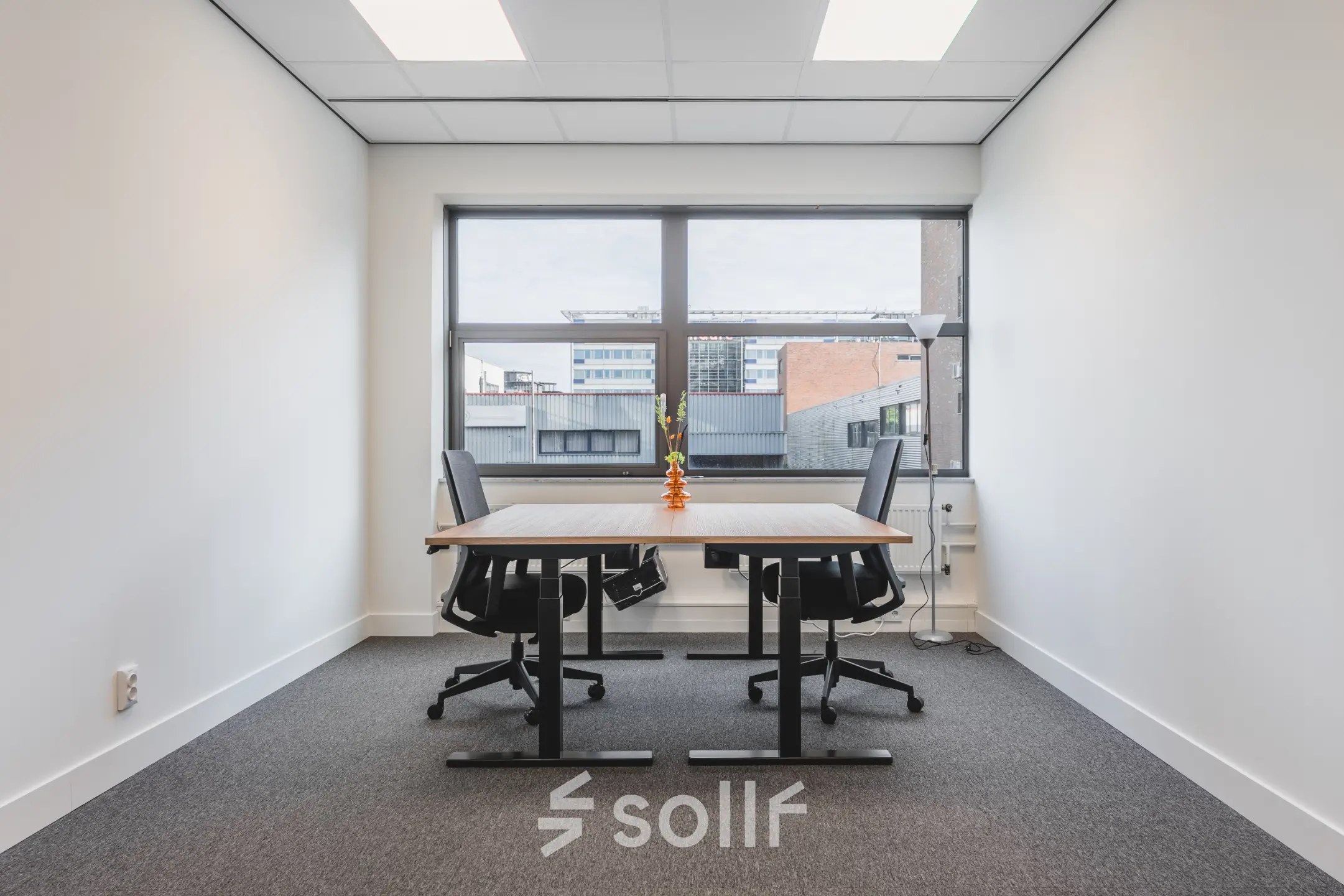 Modern office space at Veluwezoom 15, Almere Stad, featuring two desks with chairs and a large window offering natural light, ideal for office space rental.