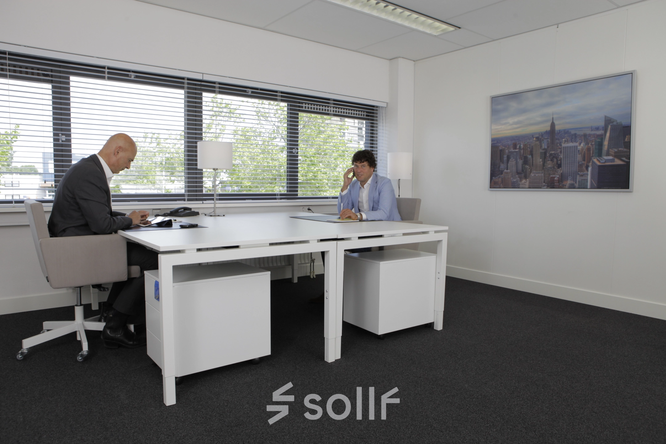 Two people work at a sleek table in a bright office at Europalaan 16, Alphen aan den Rijn, ideal for office space rental.
