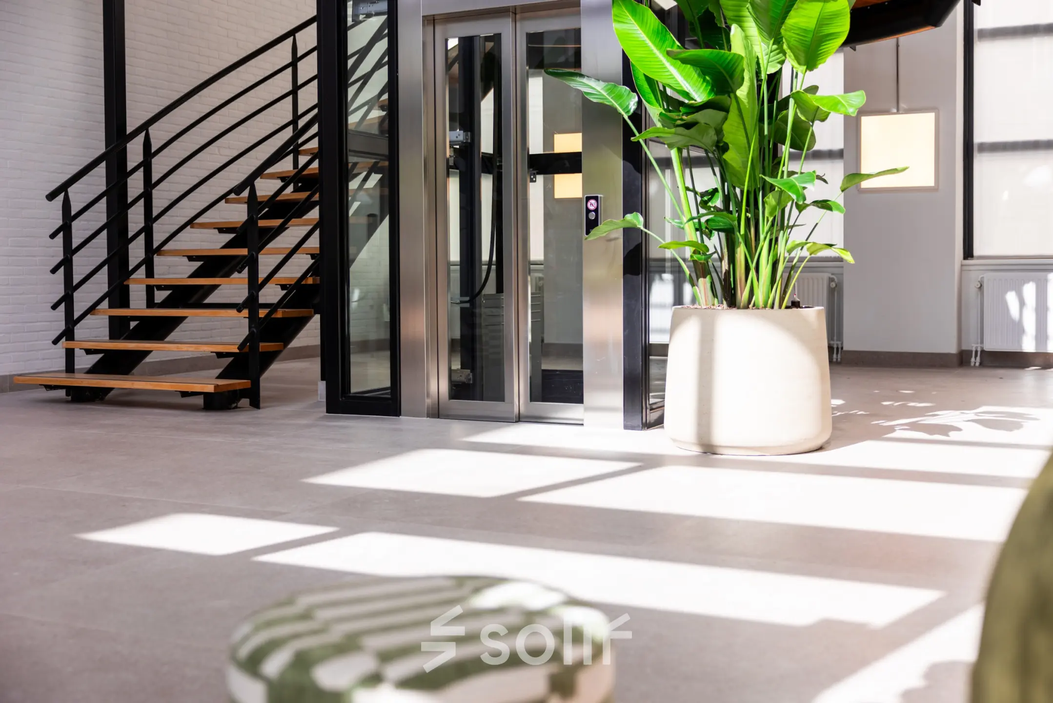 Bright and modern office lobby with a staircase, elevator, and large potted plant at Maanlander 43, Amersfoort Calveen. Ideal for office space rental.