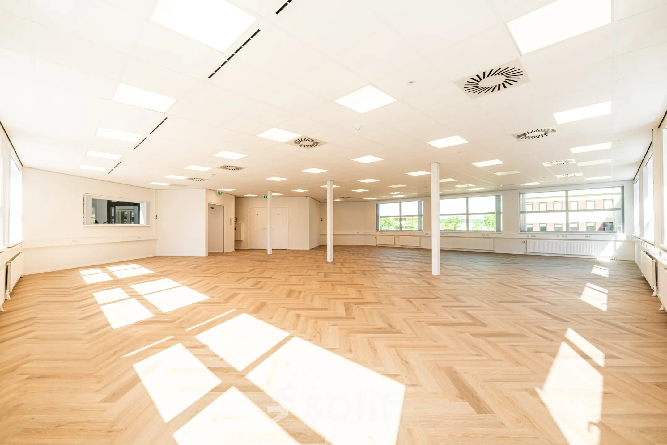 Bright, spacious office space with large windows and wood-patterned flooring at Maanlander 43, Amersfoort Calveen, available for rent.