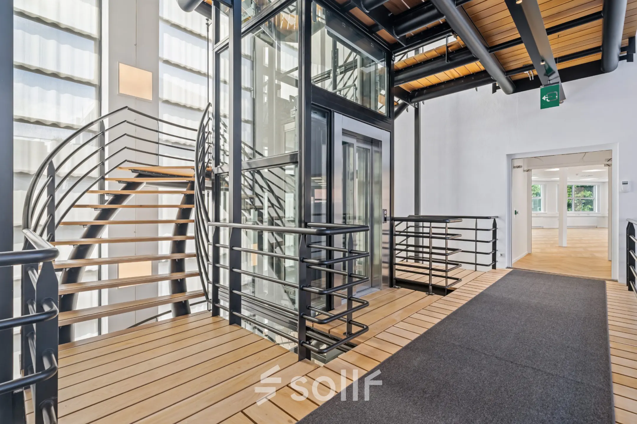 Modern office interior at Maanlander 43, Amersfoort Calveen with sleek elevator, spiral staircase, and wooden flooring. Ideal office space rental opportunity.