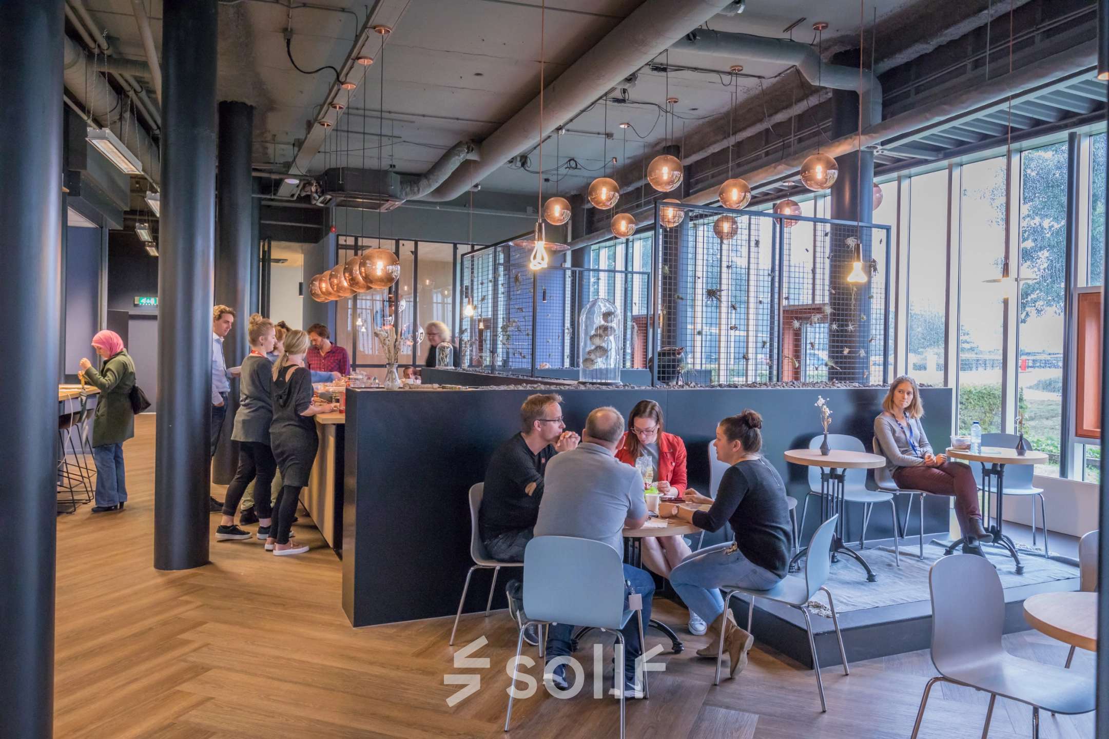 Modern interior at Maanlander 47, Amersfoort Calveen, with people engaging in conversations and enjoying the office lounge area. Ideal space for office space rental and networking.