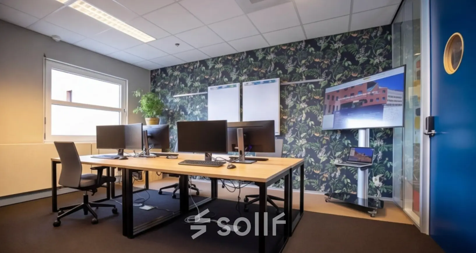 Stylish office space featuring multiple computer workstations, a large screen, and a plant, ideal for office space rental at Stationsplein 49, Amersfoort Centraal Station.