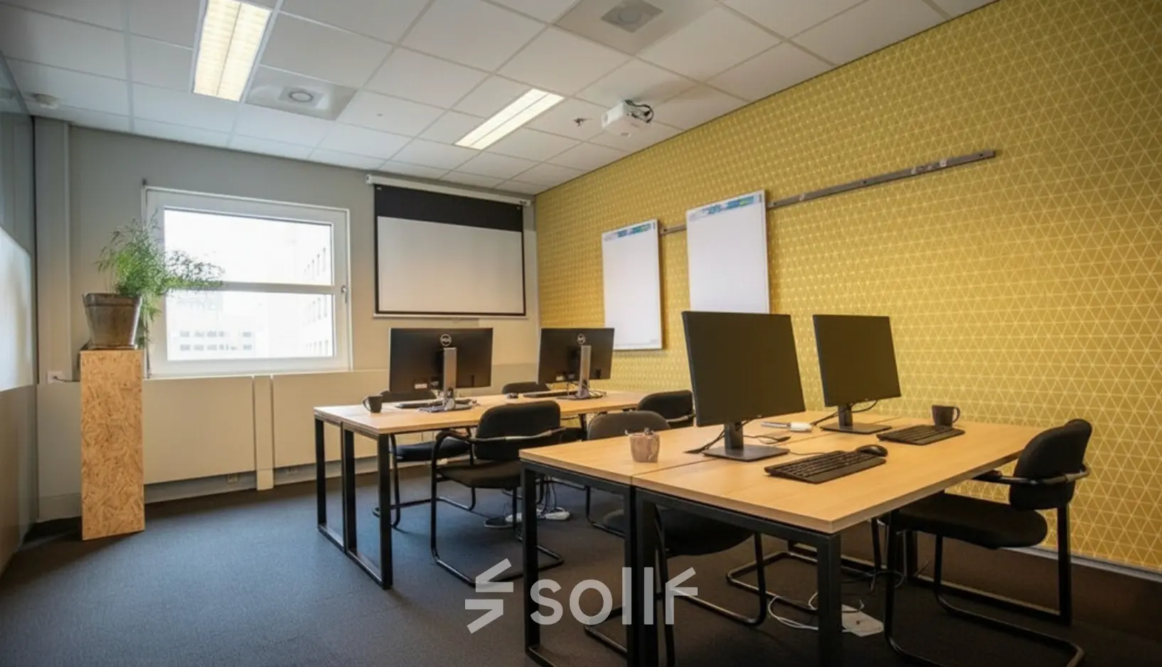 Modern office space with desks and computers at Stationsplein 49, Amersfoort Centraal Station, available for office space rental. The room features a projector and natural light.