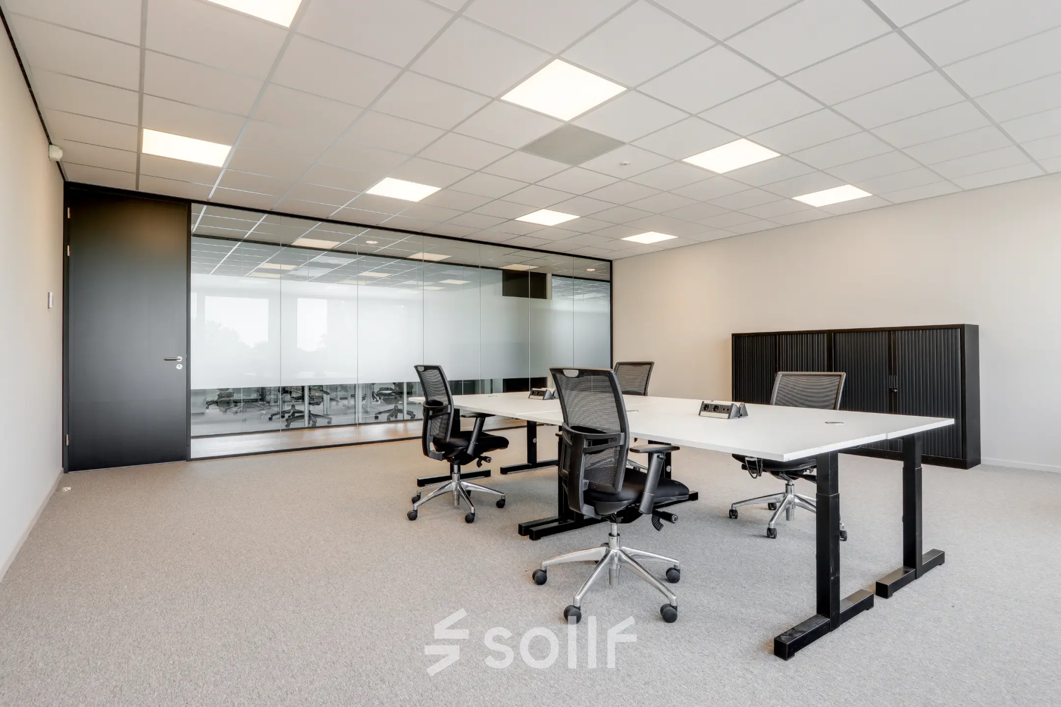 Furnished office space for rent at De Gondel 1, Amstelveen, featuring modern desks and chairs in a bright, carpeted room with glass partitions.