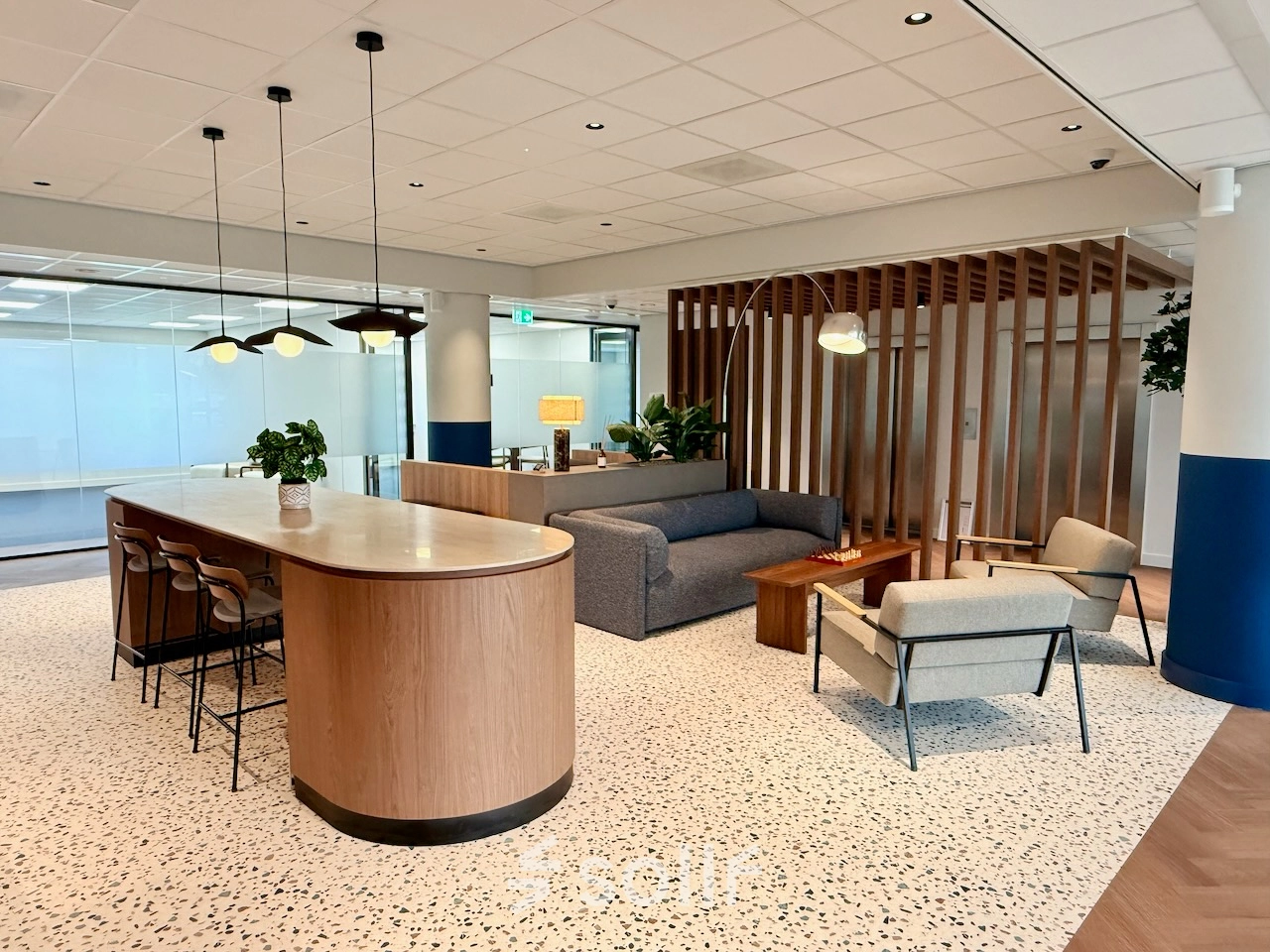 Modern office space with a sleek wooden counter, comfortable seating, and stylish lighting at Professor E.M. Meijerslaan 1, Amstelveen. Perfect for office space rental needs.