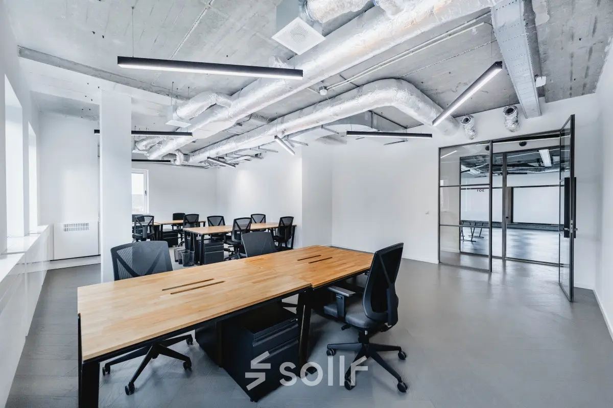 Spacious office space for rent at H.J.E. Wenckebachweg 90-108, showcasing modern interiors with industrial-style ceilings and sleek work desks, perfect for collaborative work in Amsterdam Amstel Business Park.