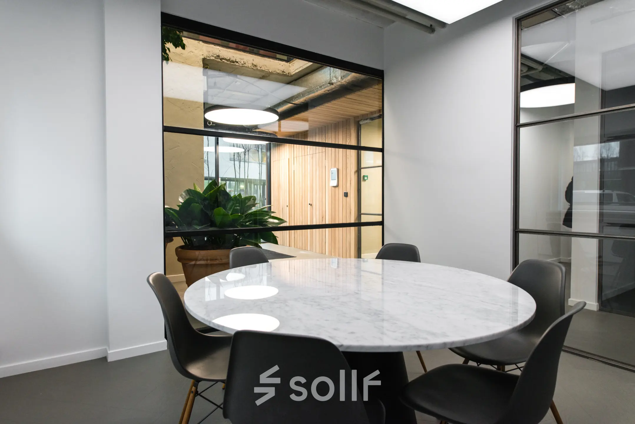 A furnished meeting room with a round marble table and six chairs in a modern office available for rent at Amsterdam Amstel Business Park.